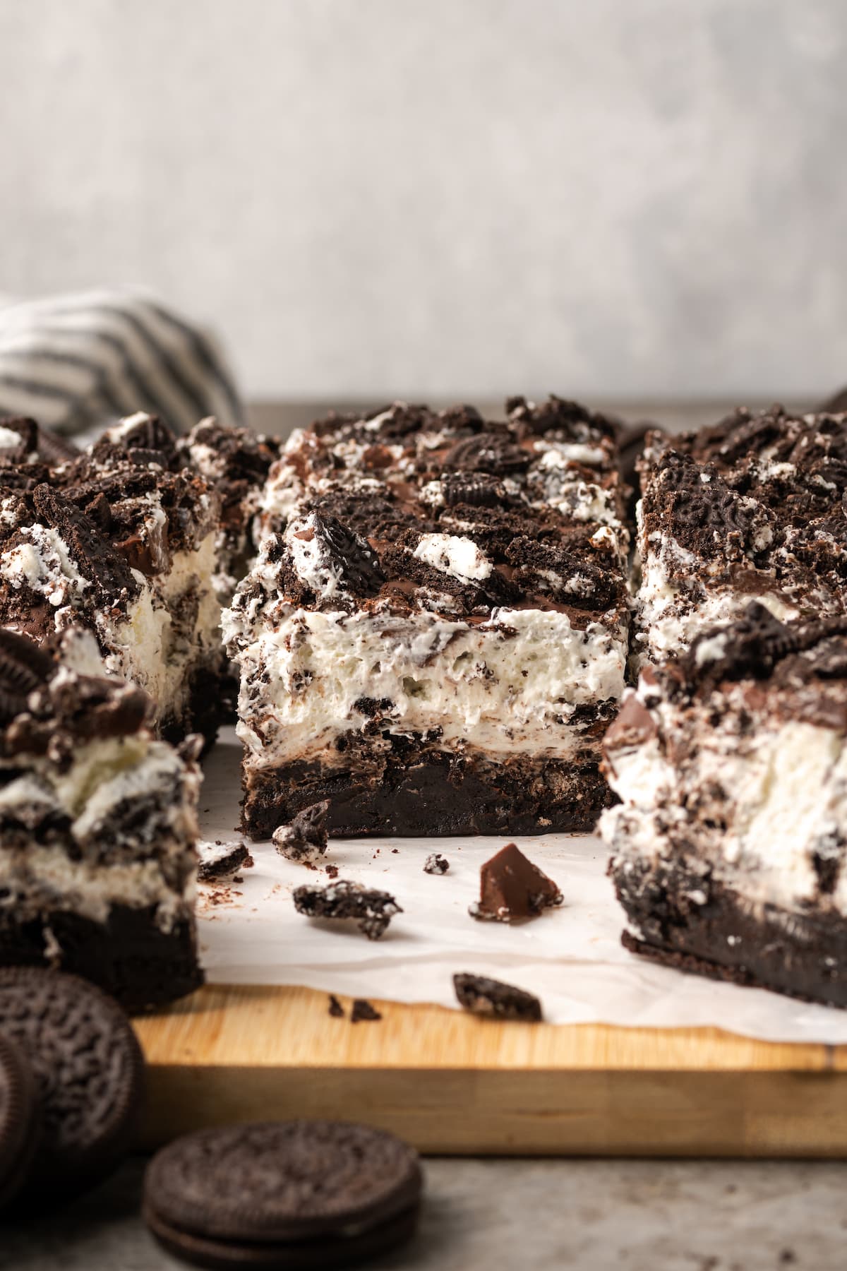 Oreo brownies on a wooden platter next to chopped Oreo cookies.