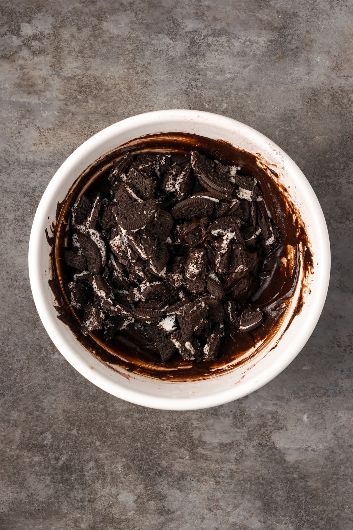 Chopped Oreos added to a bowl of chocolate brownie batter.