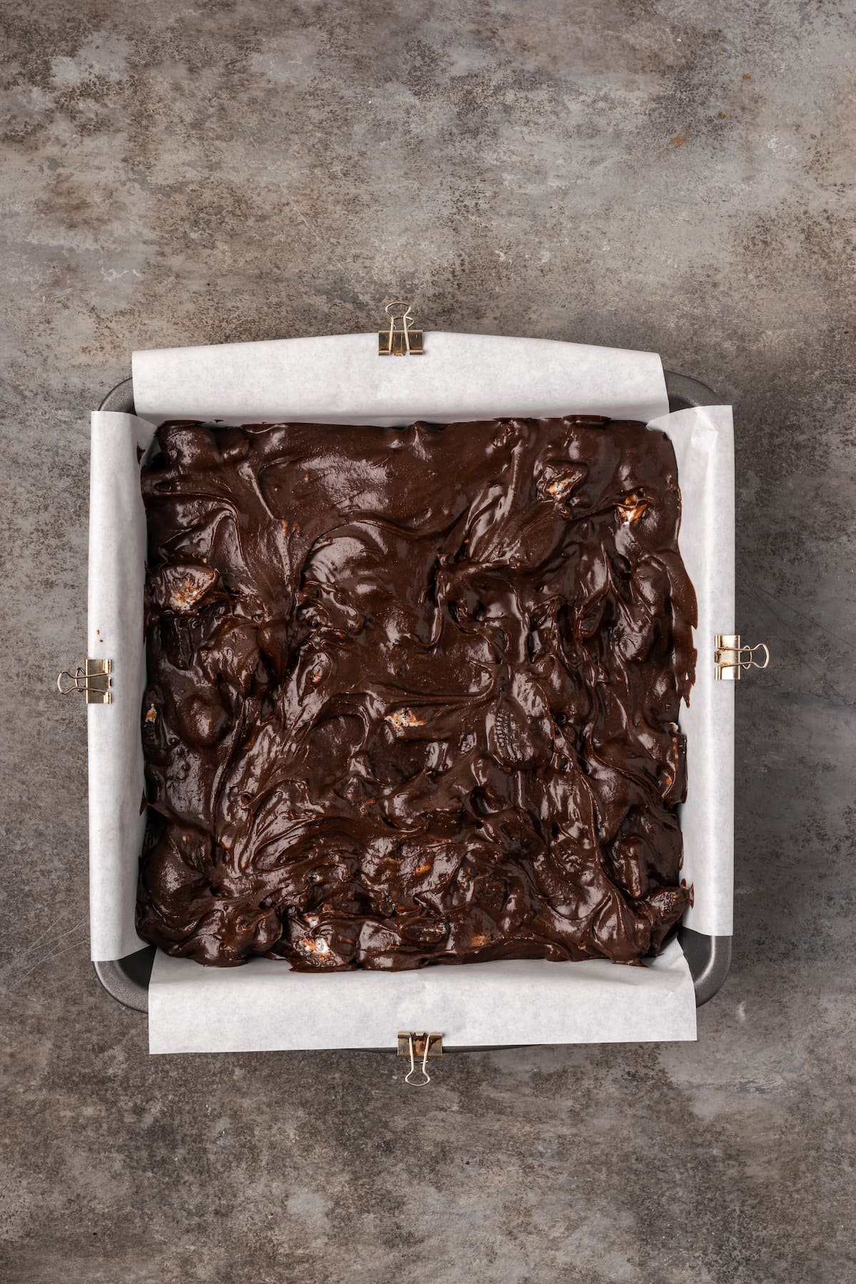 Oreo brownie batter in a square parchment-lined baking pan.