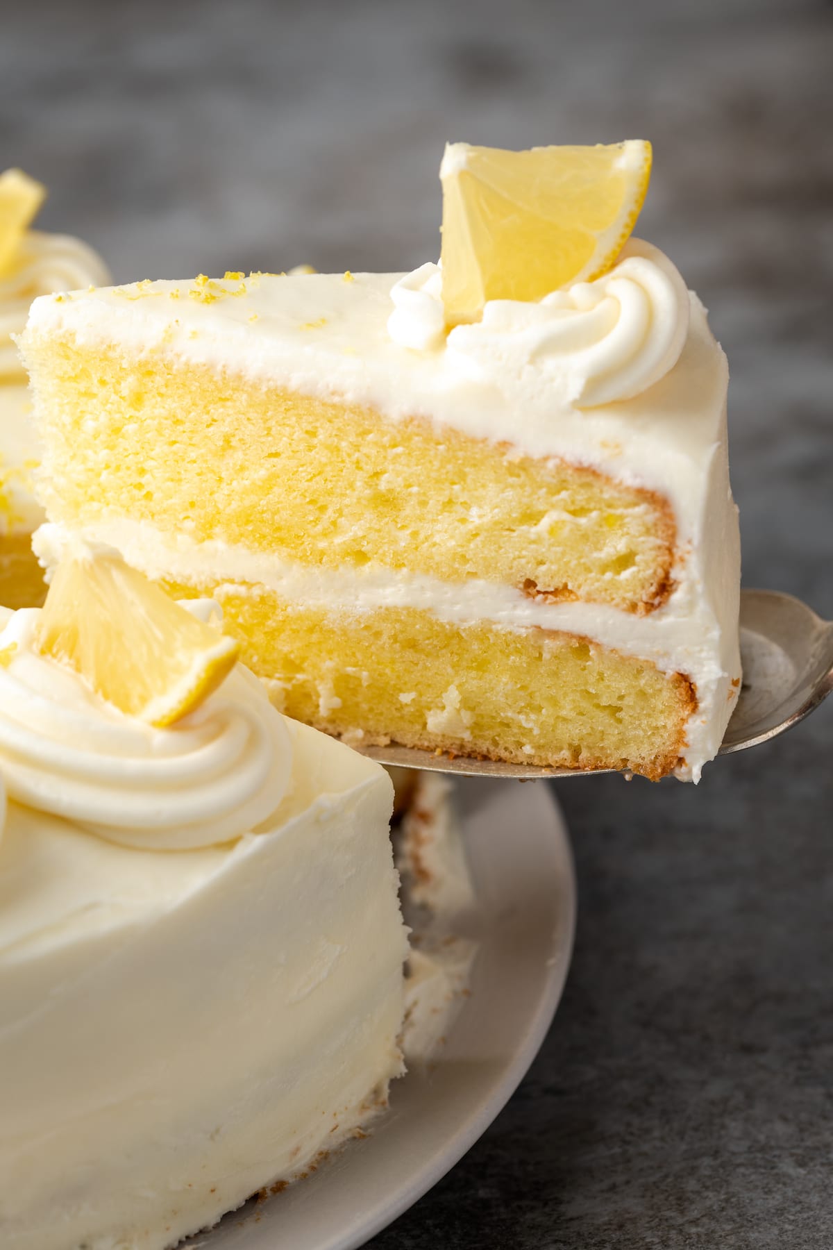 A slice is removed from a frosted lemonade cake.