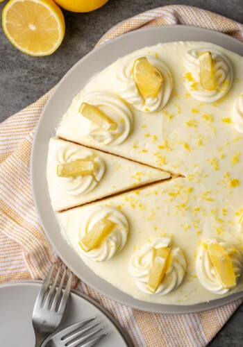 Overhead view of lemonade cake topped with frosting swirls and lemon slices, with a slice cut into it.