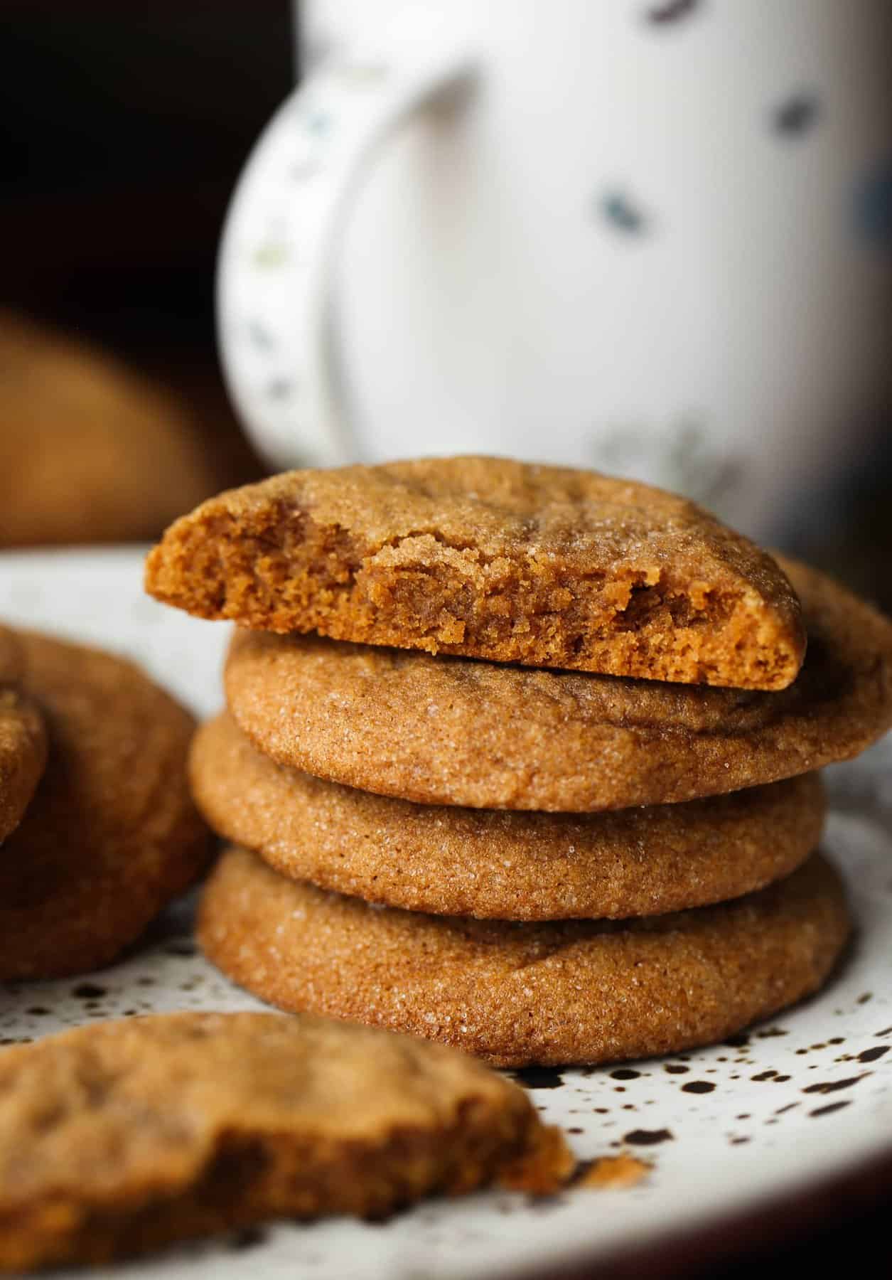 A stack of chewy molasses cookies with a bite missing from the top cookie.