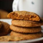 A stack of chewy molasses cookies with a bite missing from the top cookie.