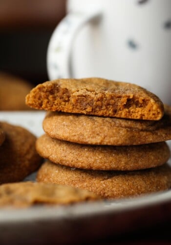 A stack of chewy molasses cookies with a bite missing from the top cookie.