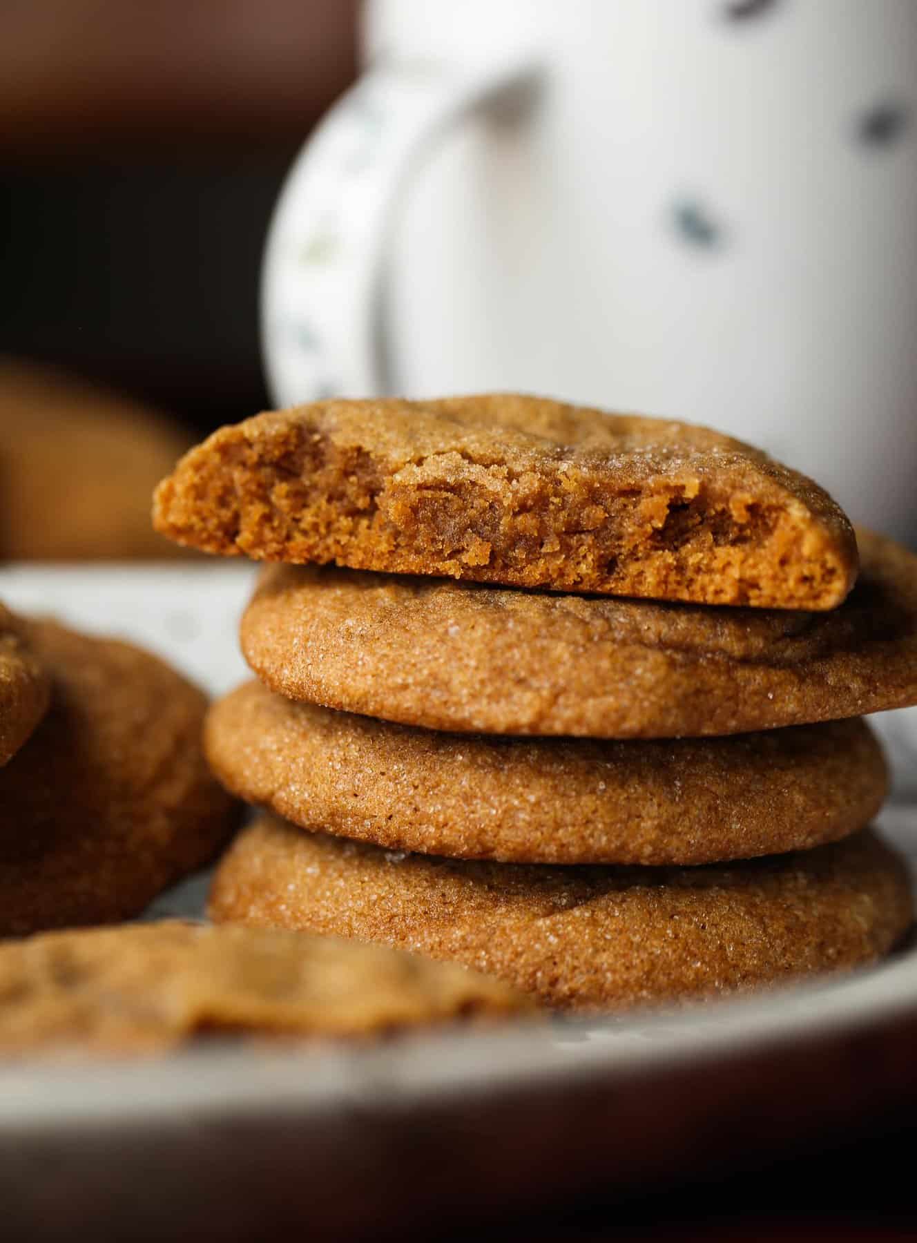 A stack of chewy molasses cookies with a bite missing from the top cookie.