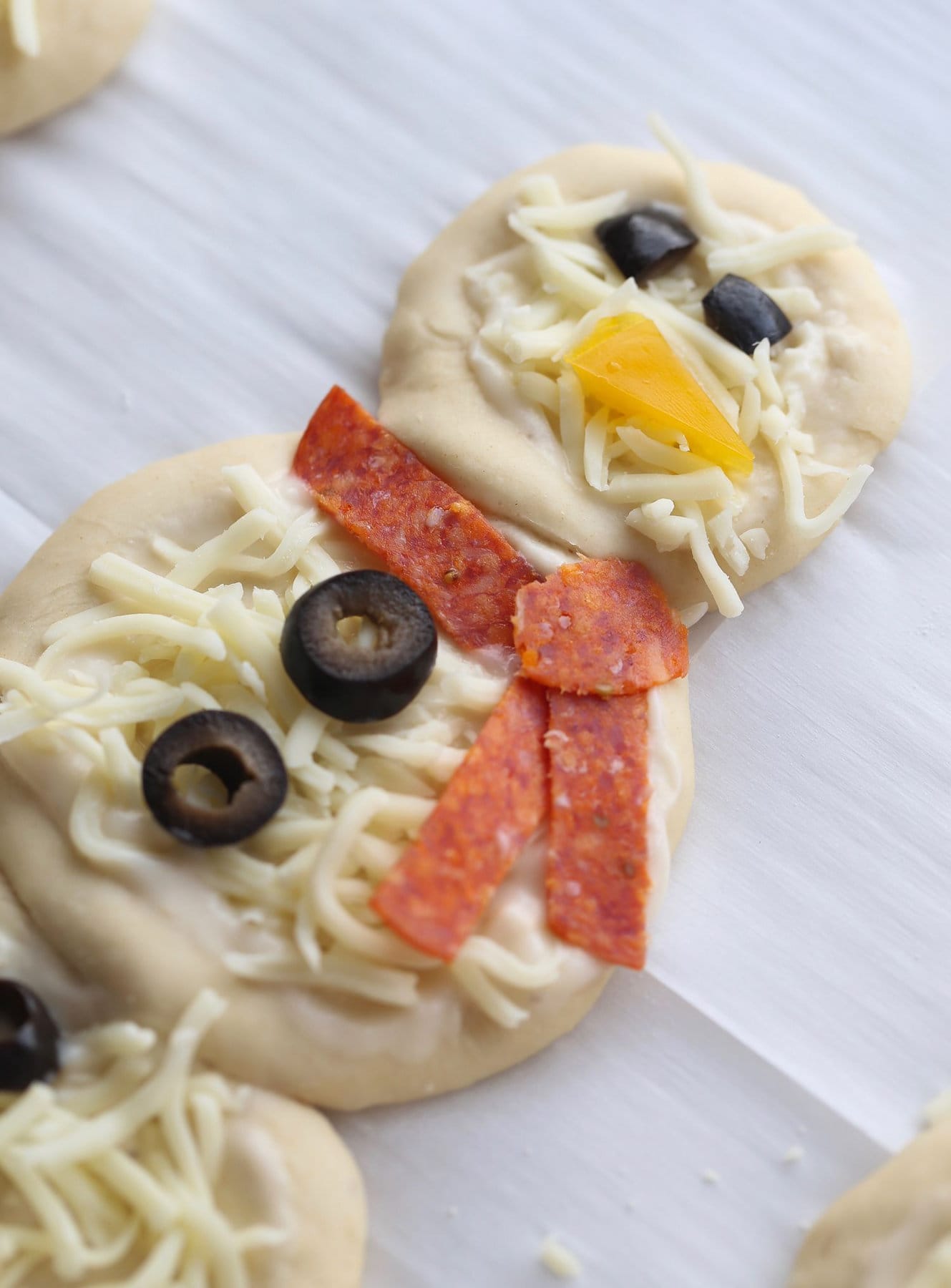 Snowman pizza with toppings displayed in a snowman design 