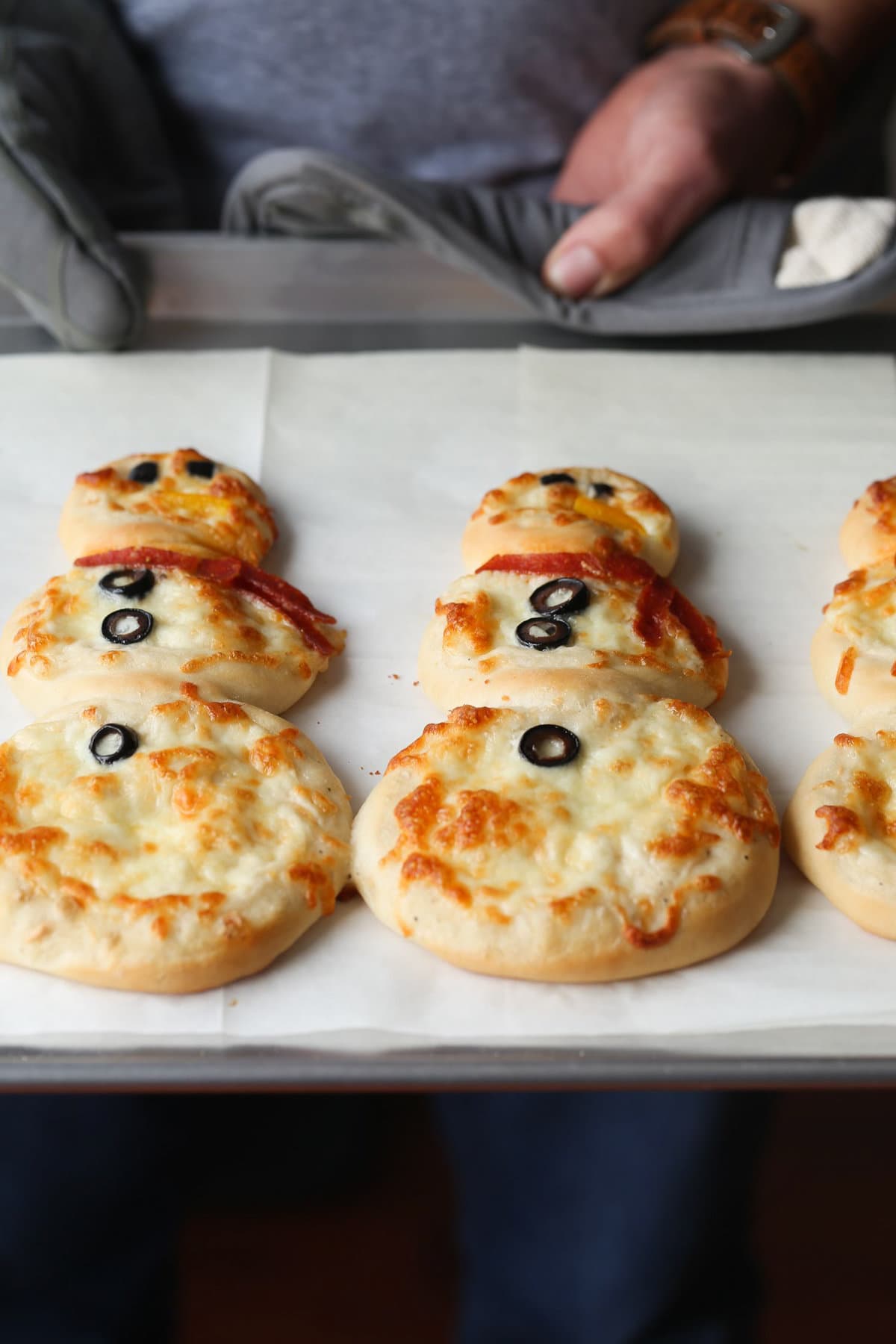 Baked snowman pizza on a baking sheet