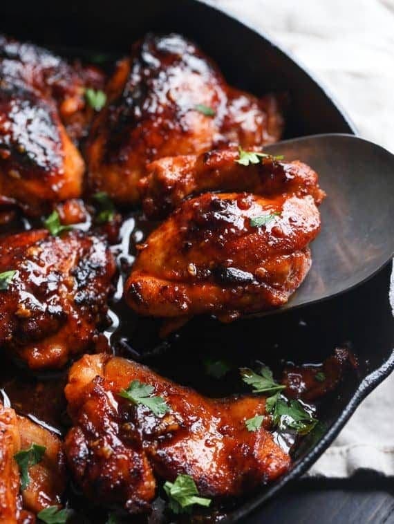 Honey chipotle chicken is lifted from a skillet with a spoon.