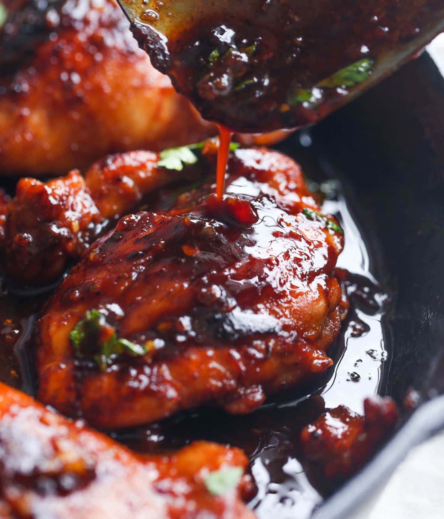 Chipotle sauce is drizzled over honey chipotle chicken thighs in a skillet.