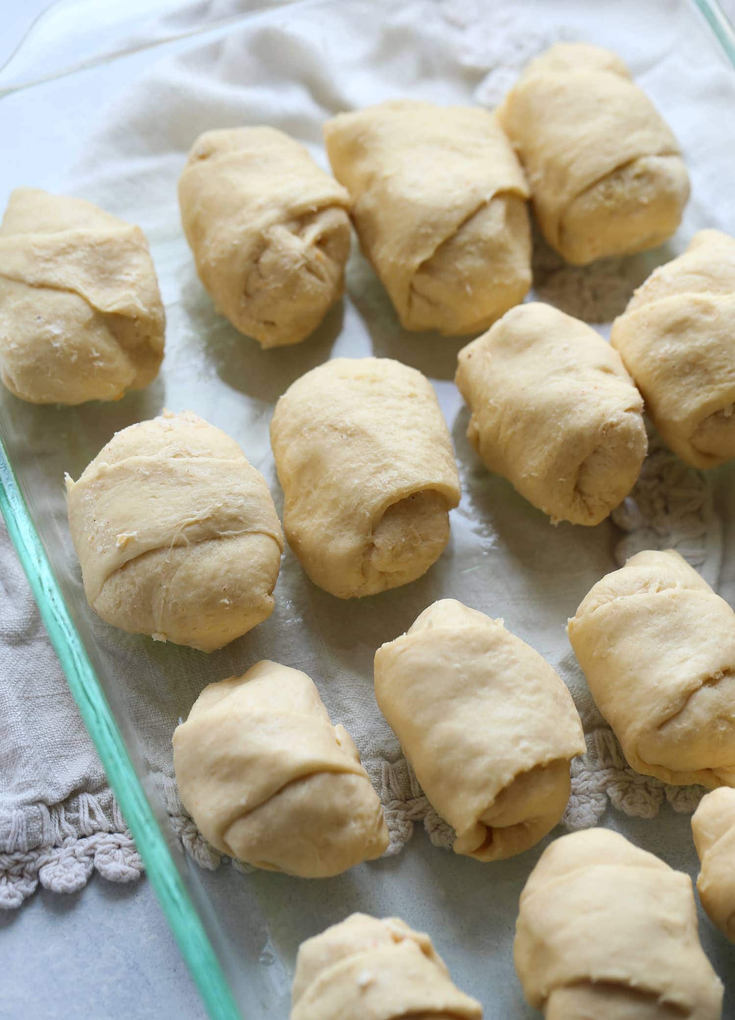 crescent roll dough wrapped around a mixture of chicken and cheese in a 9x13 glass baking dish