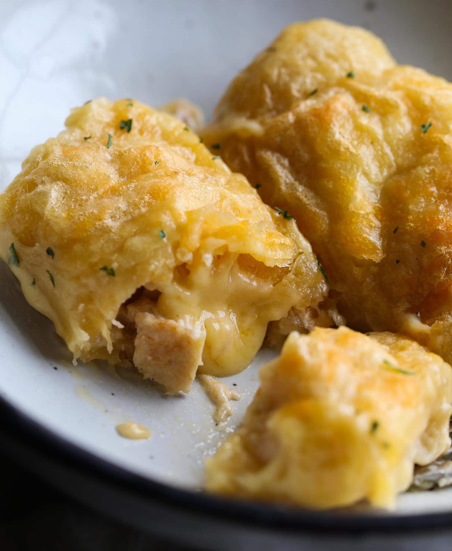 Melted cheese and chicken inside a baked crescent roll on a plate