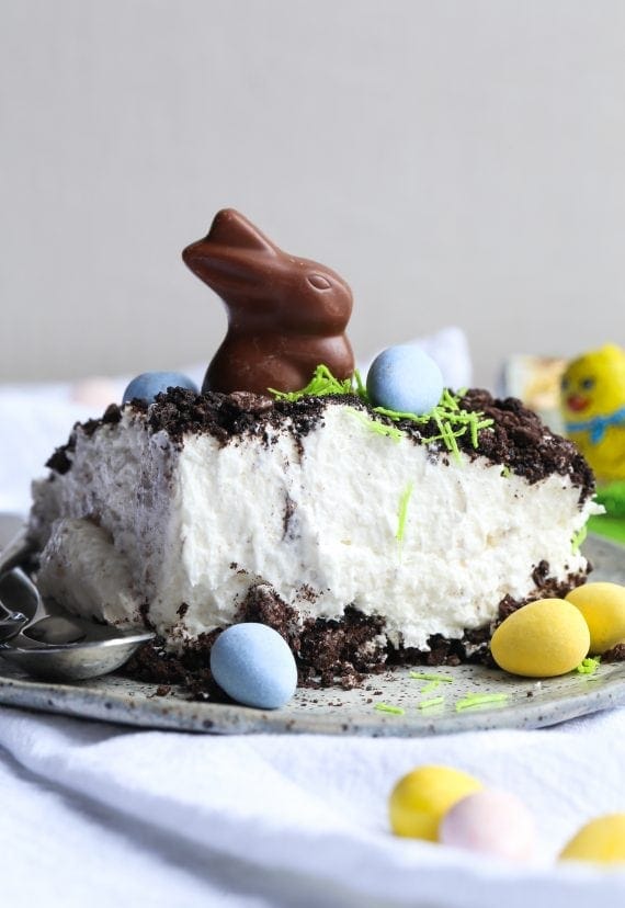 A slice of Easter Bunny Dirt Cake topped with a chocolate bunny, surrounded by mini eggs.