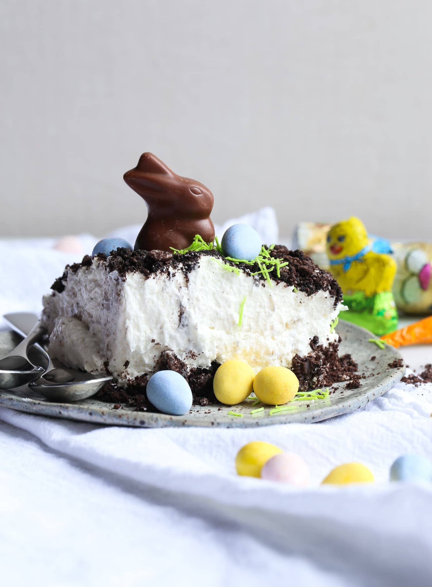 A slice of Easter Bunny Dirt Cake topped with a chocolate bunny, surrounded by mini eggs.