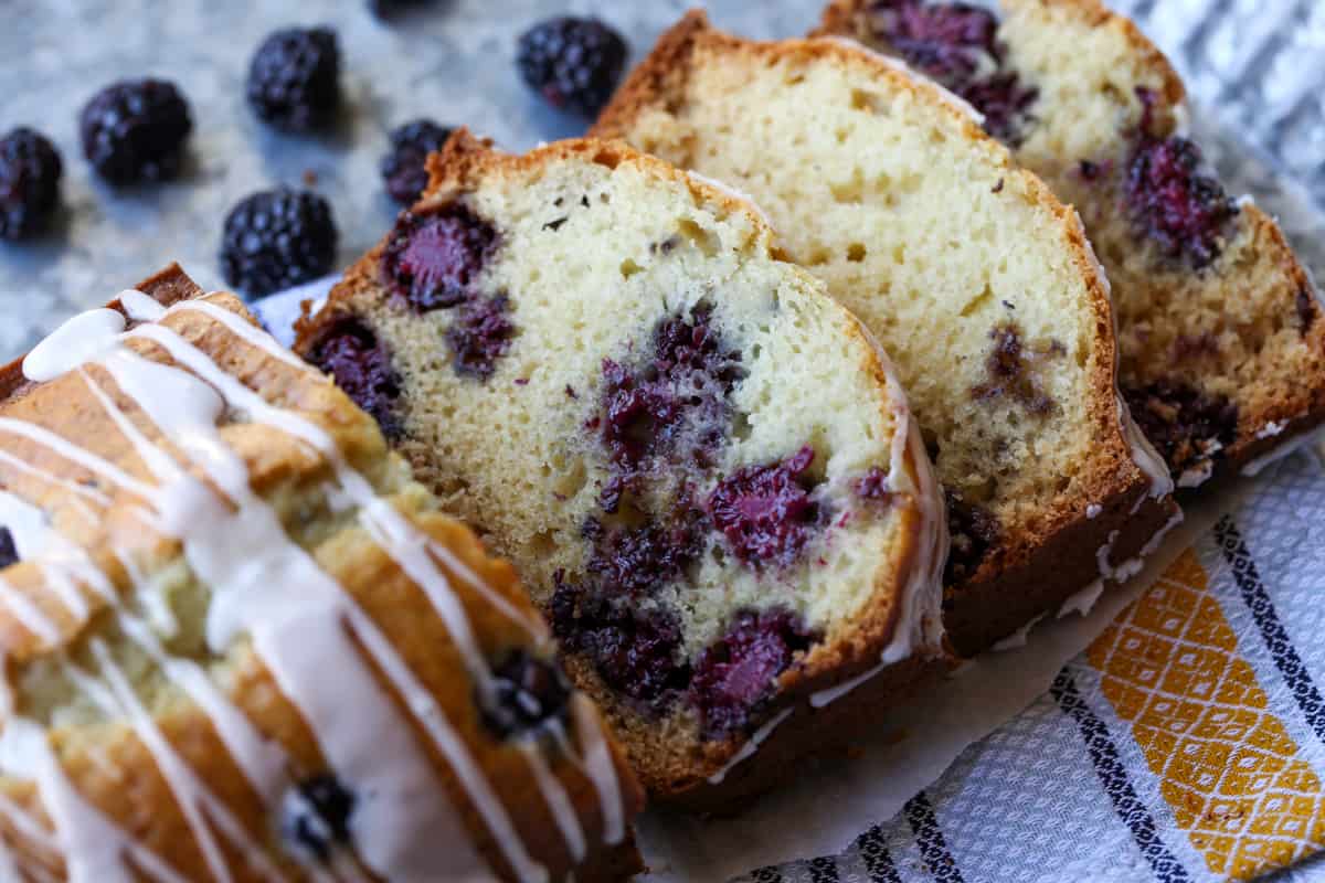 A sliced loaf of blackberry bread with vanilla icing drizzled on top. 