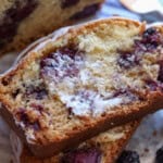 Two slices of blackberry bread stacked with butter spread on the top and a white icing drizzled