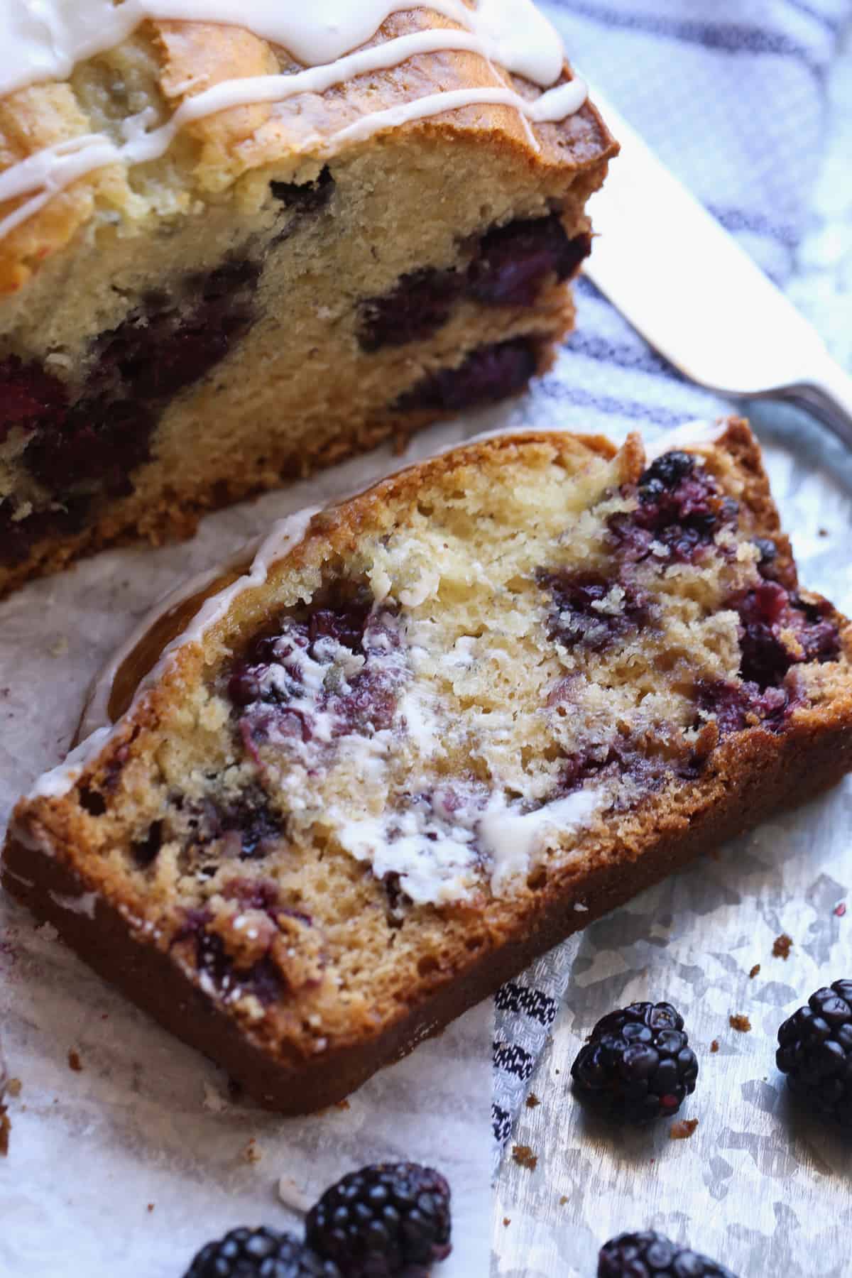 A slice of blackberry bread spread with butter on a piece of parchment paper