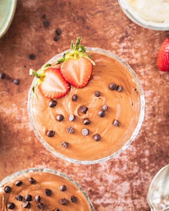 Chocolate mousse with chocolate chips and a sliced strawberry.