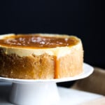 Caramel Instant Pot cheesecake on a white cake stand.