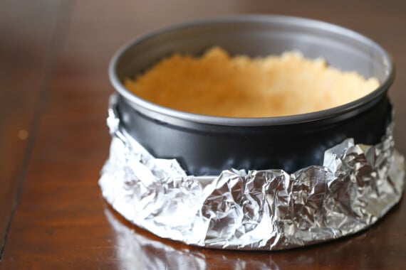 Ritz cracker cheesecake crust in a springform pan wrapped with aluminum foil.