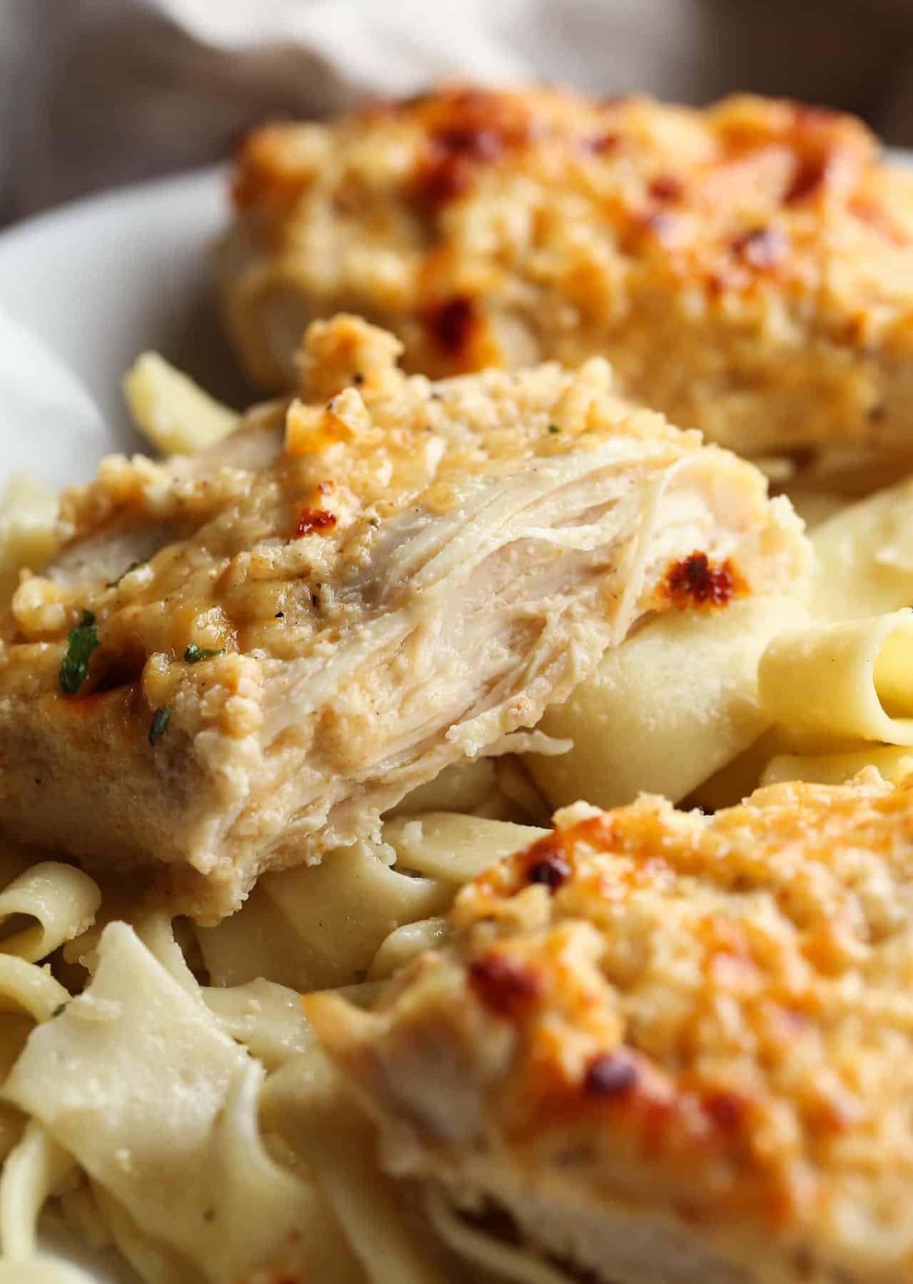 Chicken cut in half on a plate with pasta