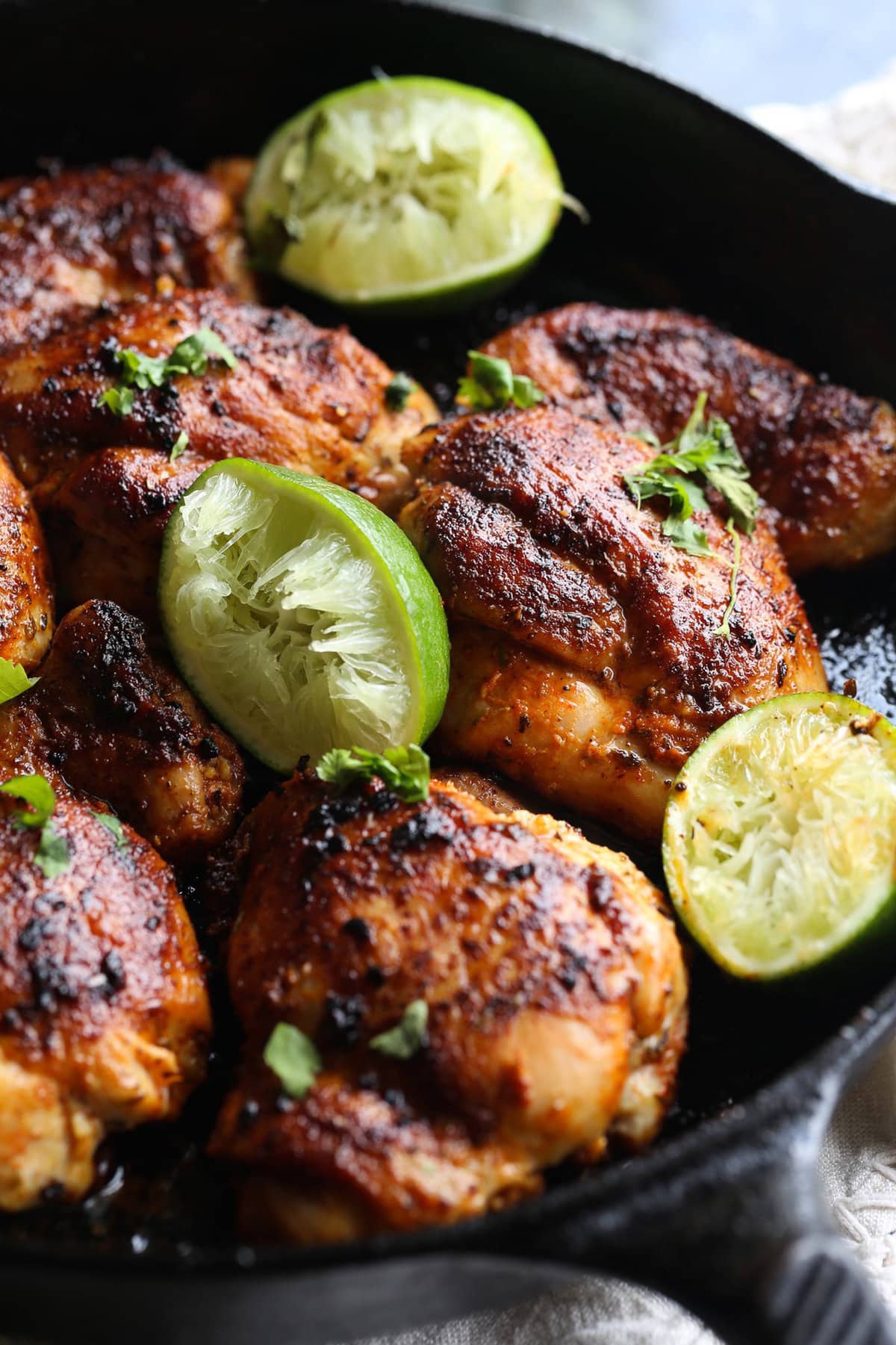 browned chicken thighs with limes in a skillet