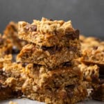 A stack of caramel oat bars surrounded by more bars on a countertop.