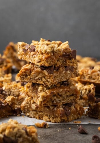 A stack of caramel oat bars surrounded by more bars on a countertop.