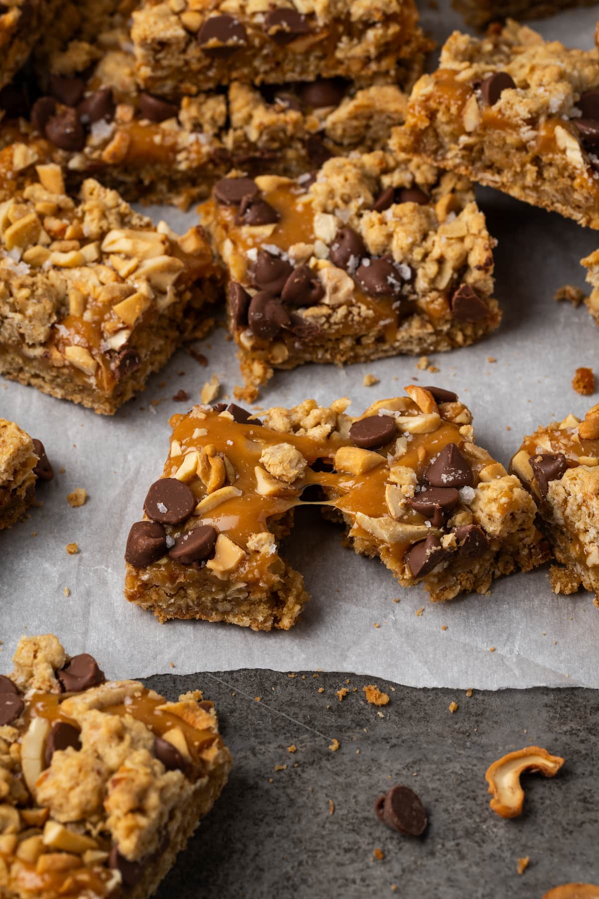 Assorted caramel oat bars on a piece of parchment paper, with one bar pulled in two.