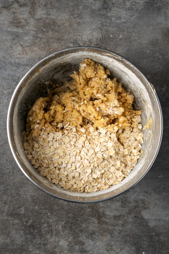 Rolled oats added to a mixing bowl with caramel oat bar ingredients.