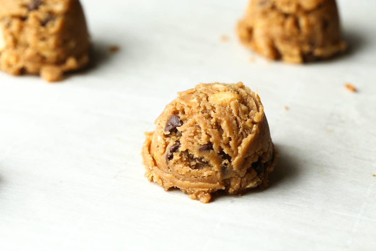 Brown butter cookie dough scooped onto a parchment lined baking sheet.