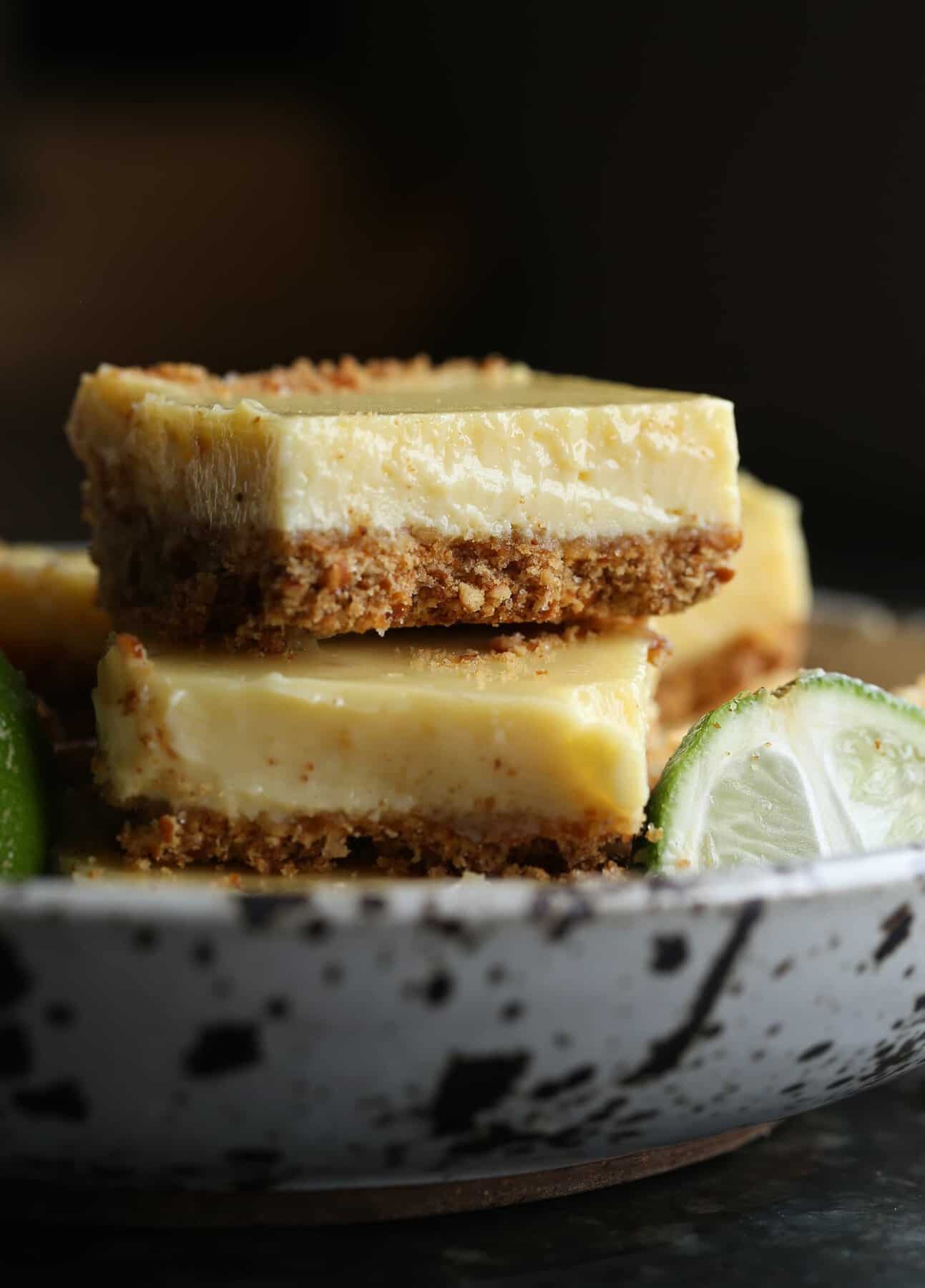 Pretzel Crusted Key Lime Bars stacked in a bowl next to a key lime wedge.