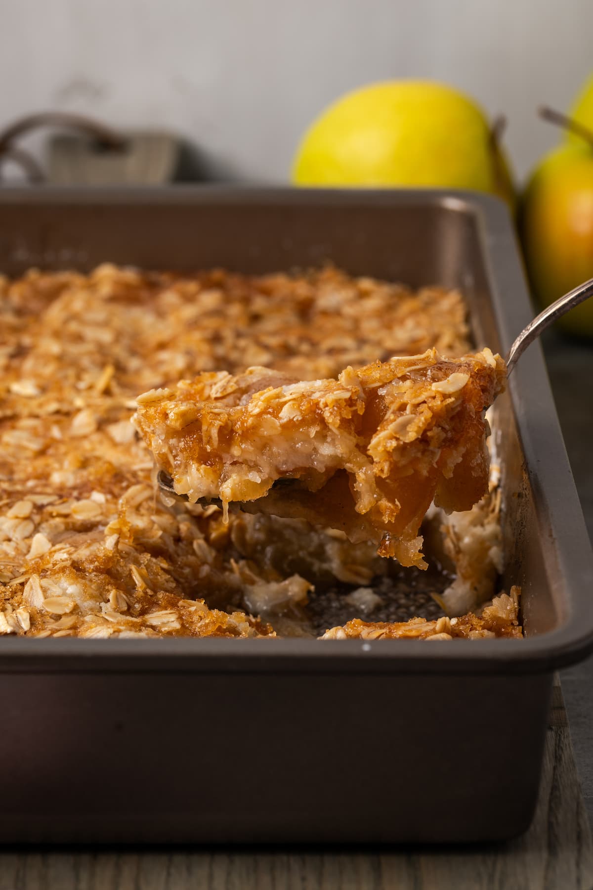 A spoon stuck lifting a serving from the corner of a baked apple dump cake in a baking pan.