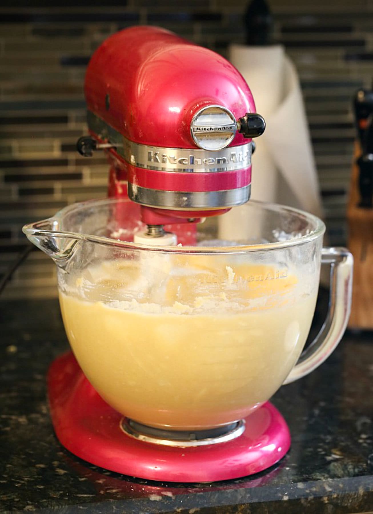 cake batter in the glass bowl of a pink stand mixer