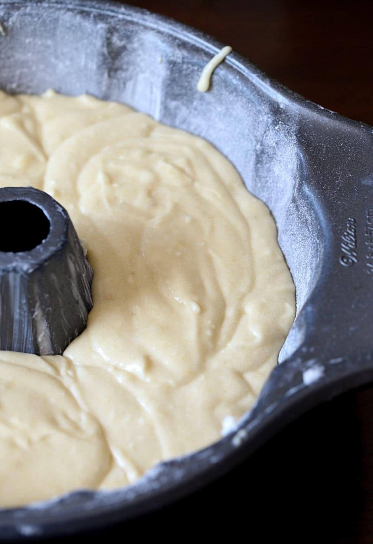 A grey bundt pan with cake batter inside