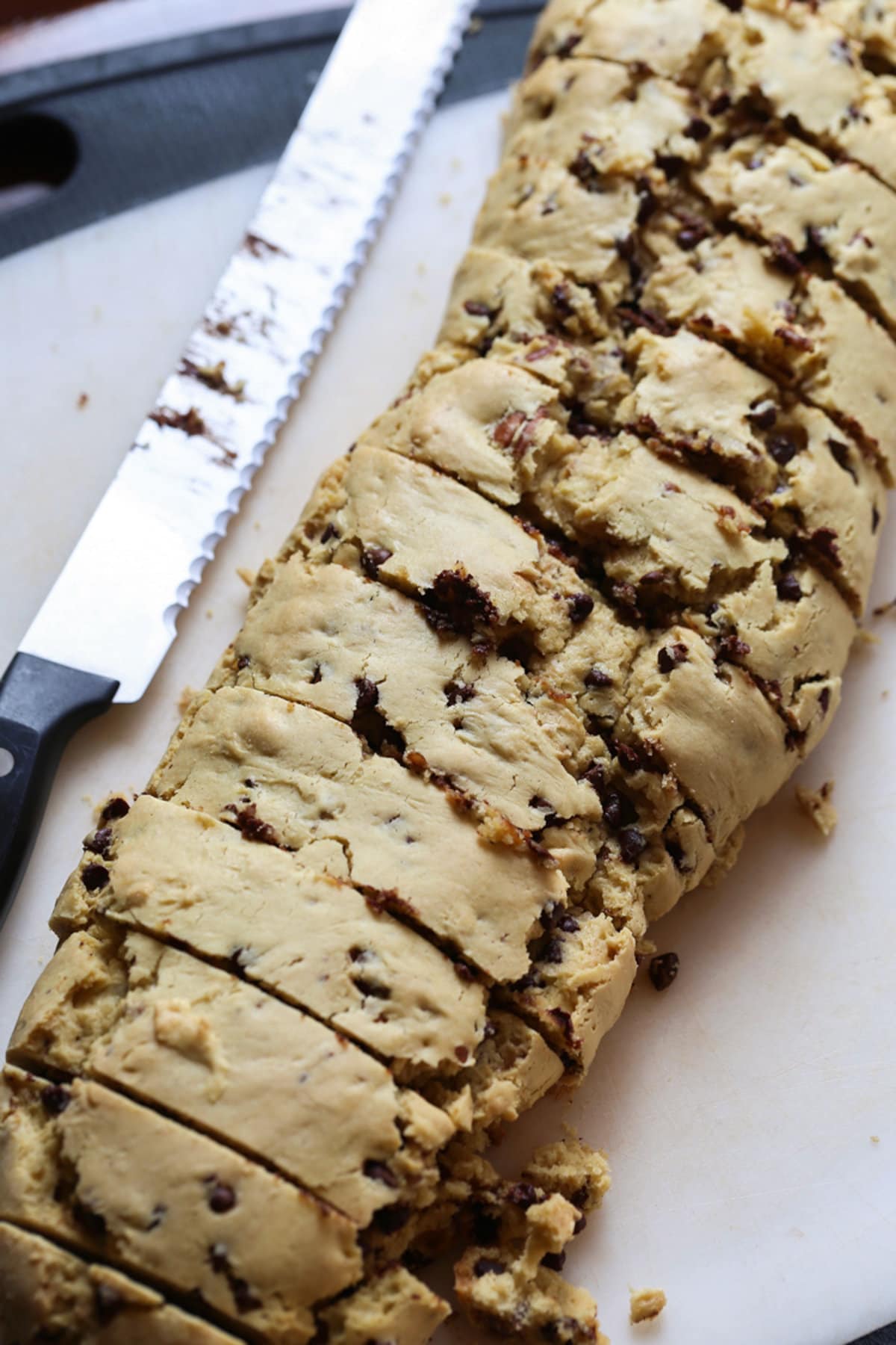A log of dough sliced into pieces with a serrated knife in the process of making biscotti using a cake mix