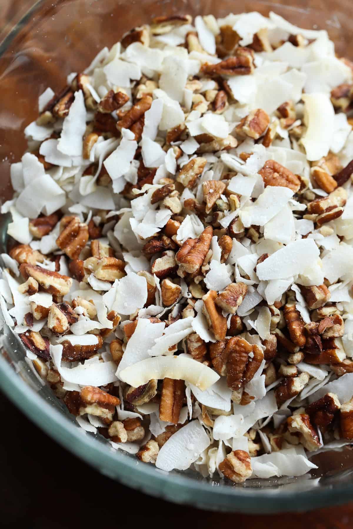 Unsweetened flaked coconut and pecans in a mixing bowl.