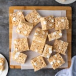 Overhead view of assorted Rice Krispie Treats on a wooden platter lined with parchment paper.