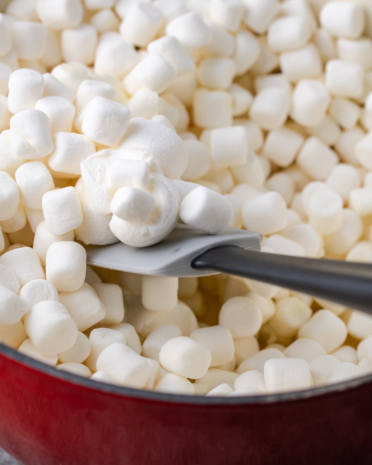 Mini marshmallows in a pot with a rubber spatula.