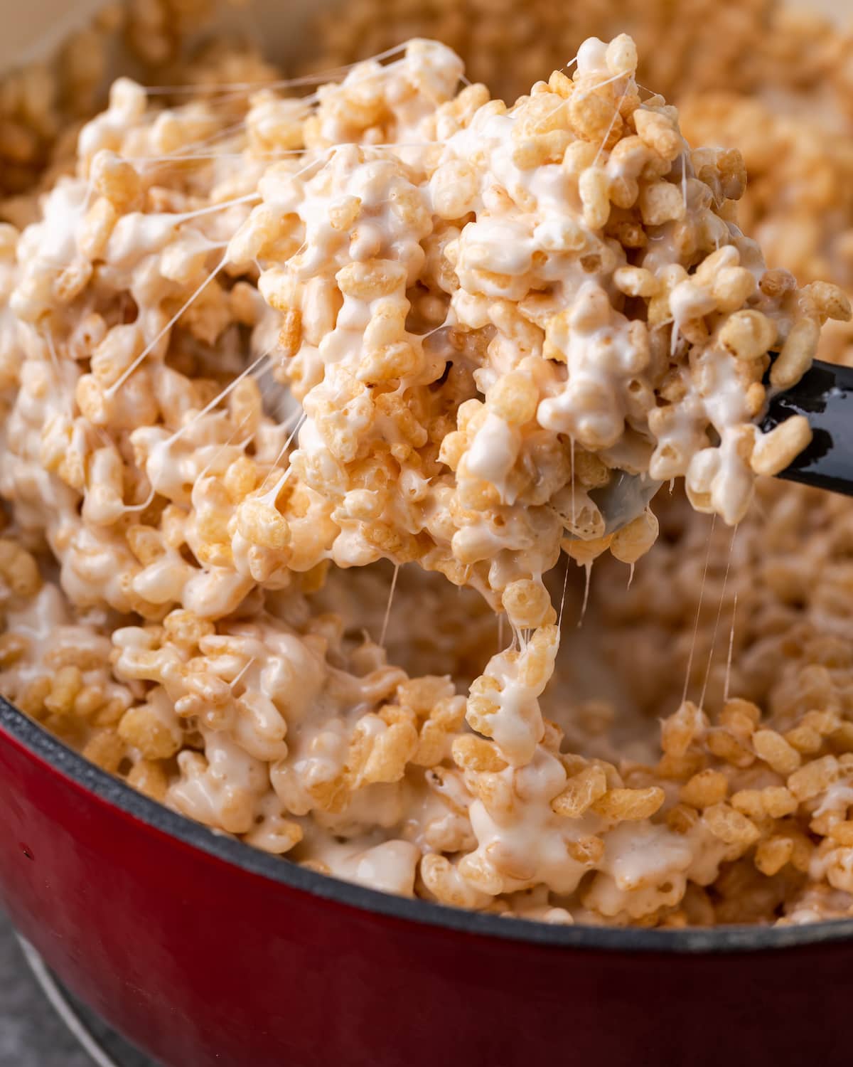 Rice Krispie cereal is combined in a pot with melted marshmallows.