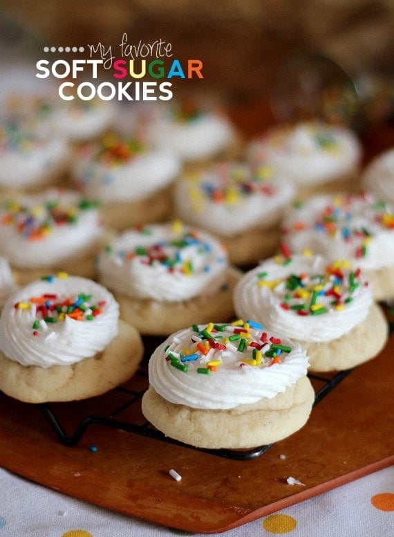 Soft sugar cookies topped with frosting and sprinkles on a wire cooling rack