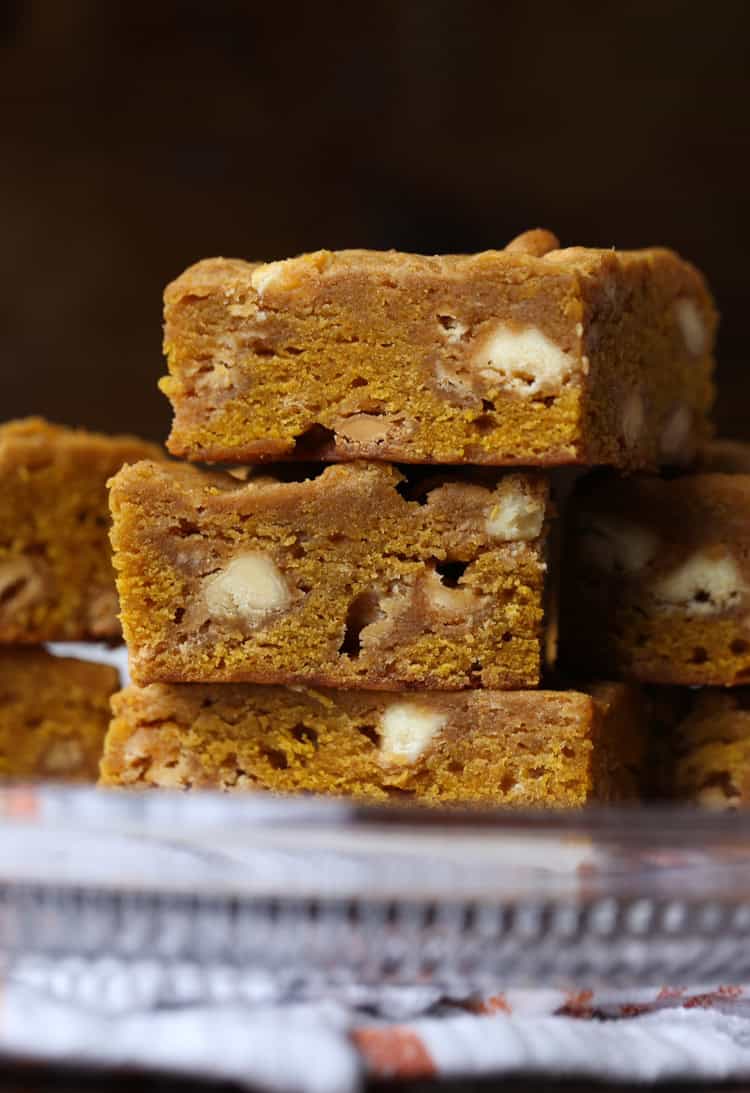 Three pumpkin blondies stacked with white chocolate chips.