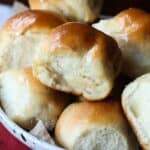 Dinner rolls stacked on a white plate.