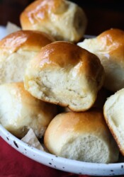 Dinner rolls stacked on a white plate.