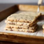 A stack of chocolate chip shortbread cookies on a lined baking sheet.