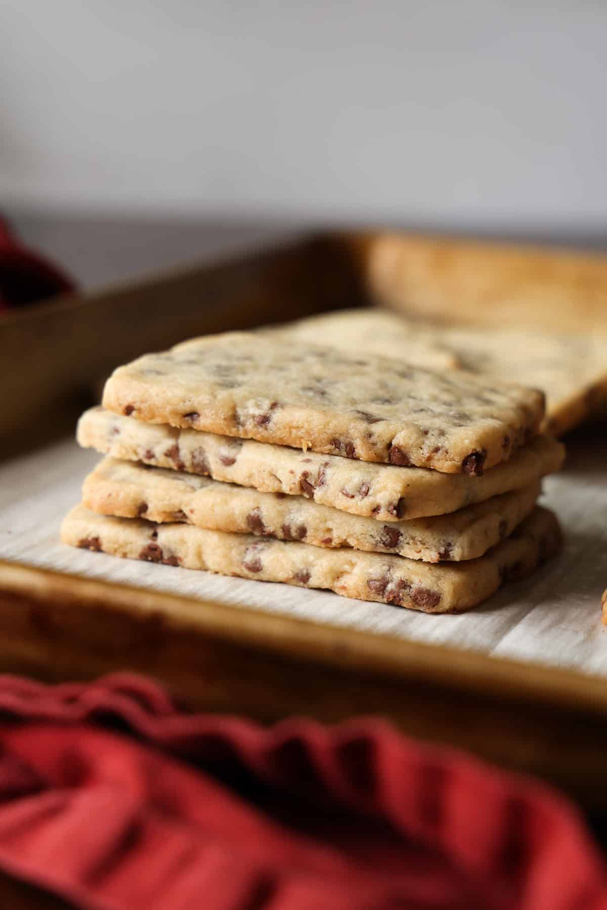 This easy chocolate chip shortbread is crisp, buttery, and loaded with mini chocolate chips. Freezer-friendly and perfect for holiday baking! A stack of chocolate chip shortbread cookies on a lined baking sheet.