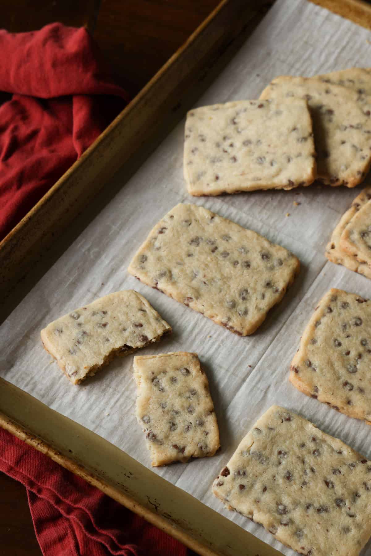 This easy chocolate chip shortbread is crisp, buttery, and loaded with mini chocolate chips. Freezer-friendly and perfect for holiday baking! Overhead view of assorted chocolate chip shortbread squares on a baking sheet.