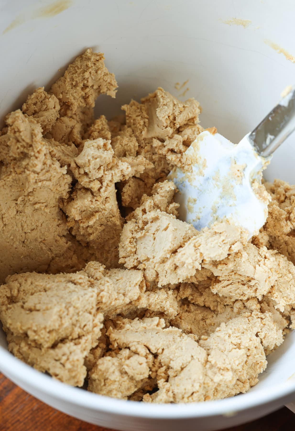 Peanut Butter and powdered sugar mixture in a white mixing bowl with a rubber spatula
