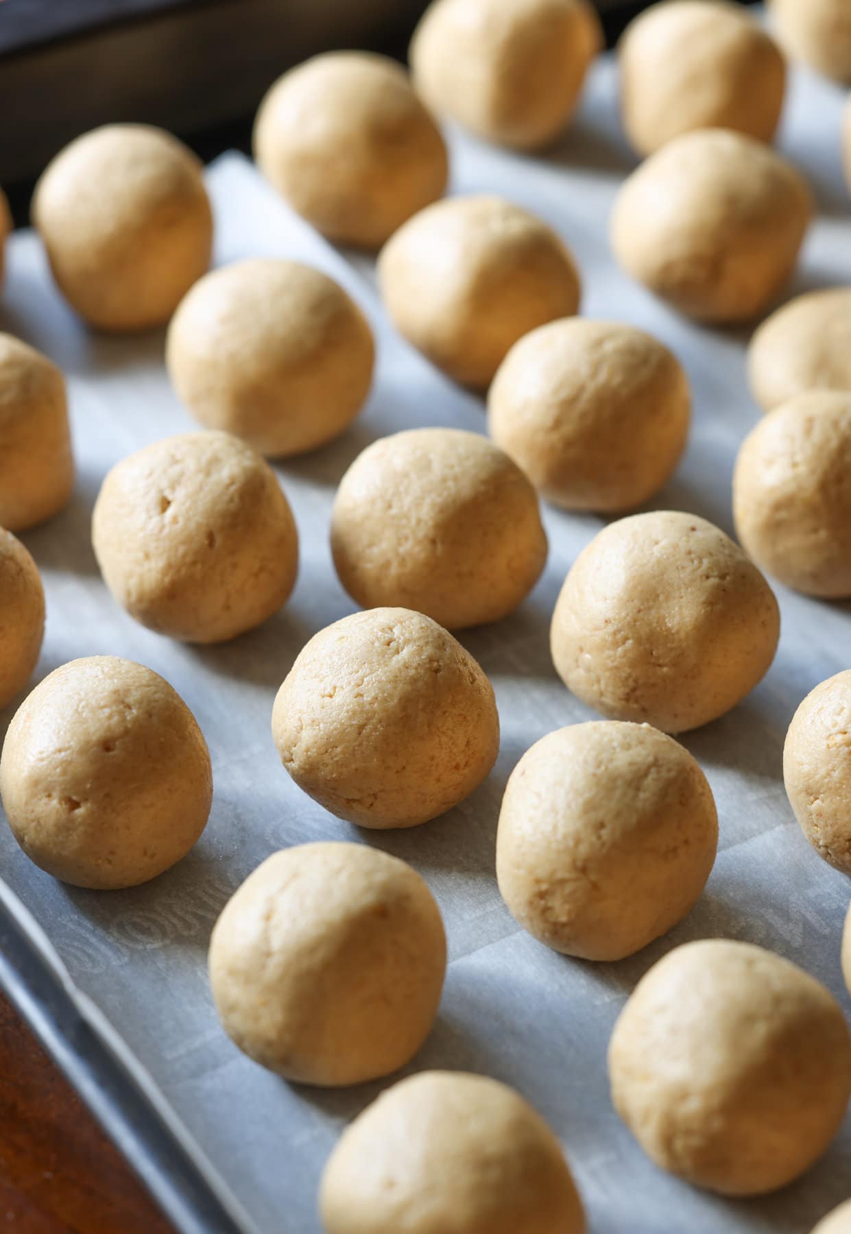 peanut butter balls rolled into balls on a parchment lined baking sheet before being dipped into chocolate