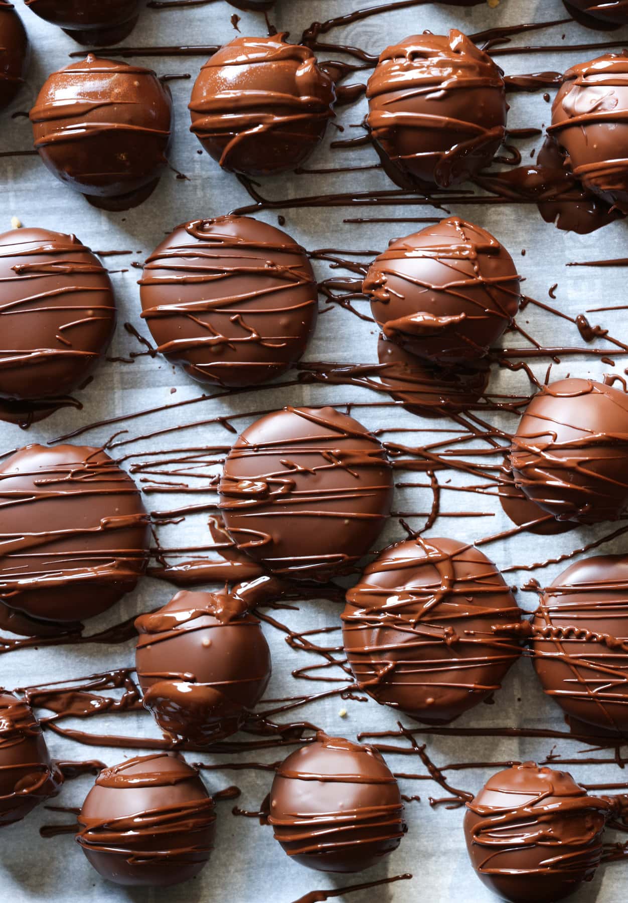 Wet melted chocolate decoratively drizzled onto peanut butter balls