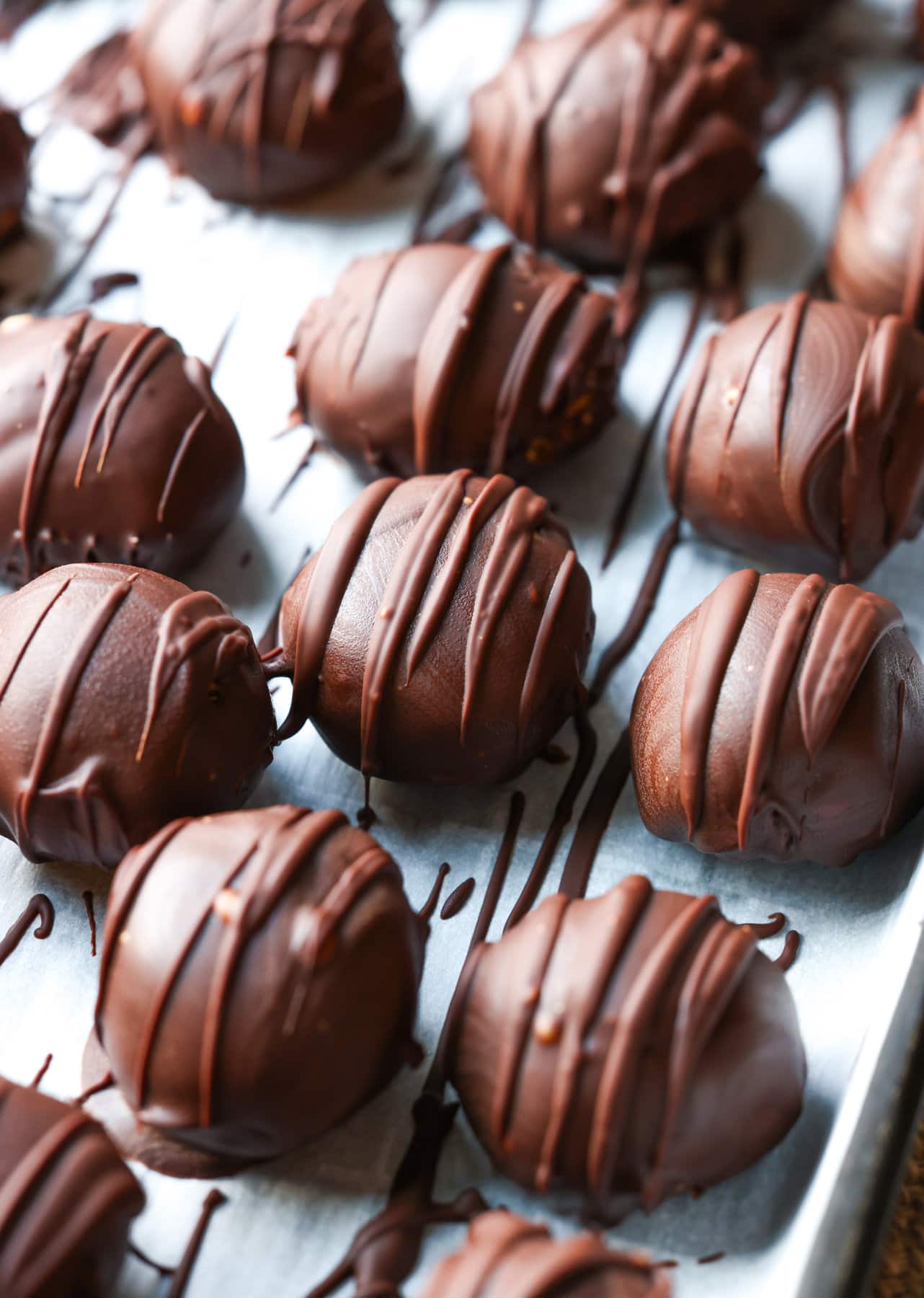 Peanut butter balls setting up after being dipped in chocolate on parchment paper